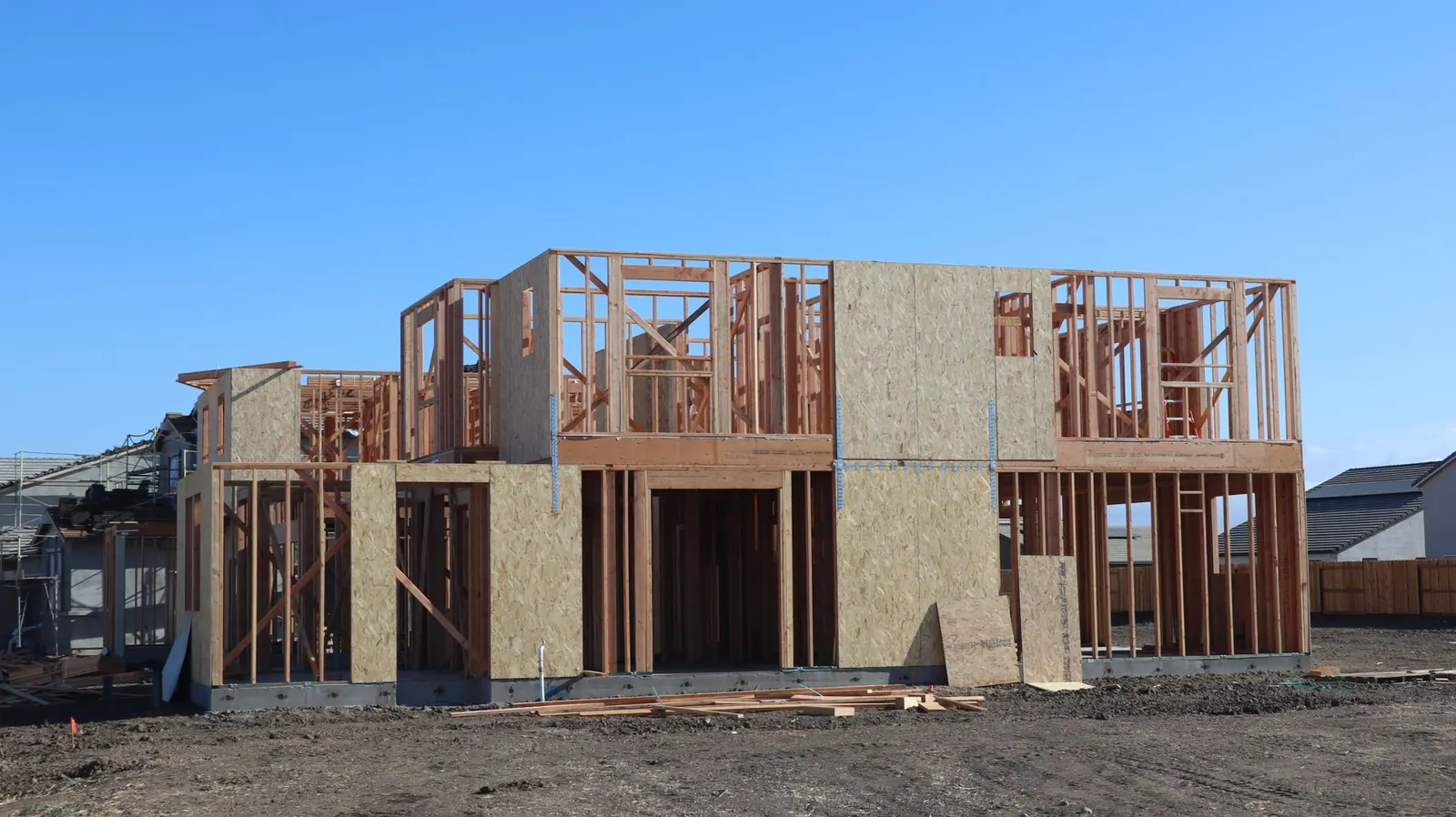 A wooden frame structure under construction for a new suburban house.